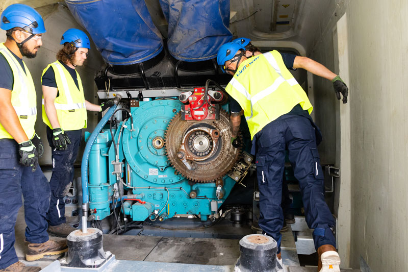Workers servicing industrial engine inside machinery compartment