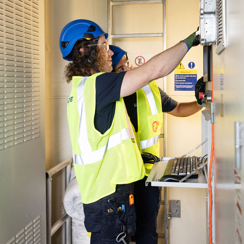 Technicians servicing electrical control panel in protective gear
